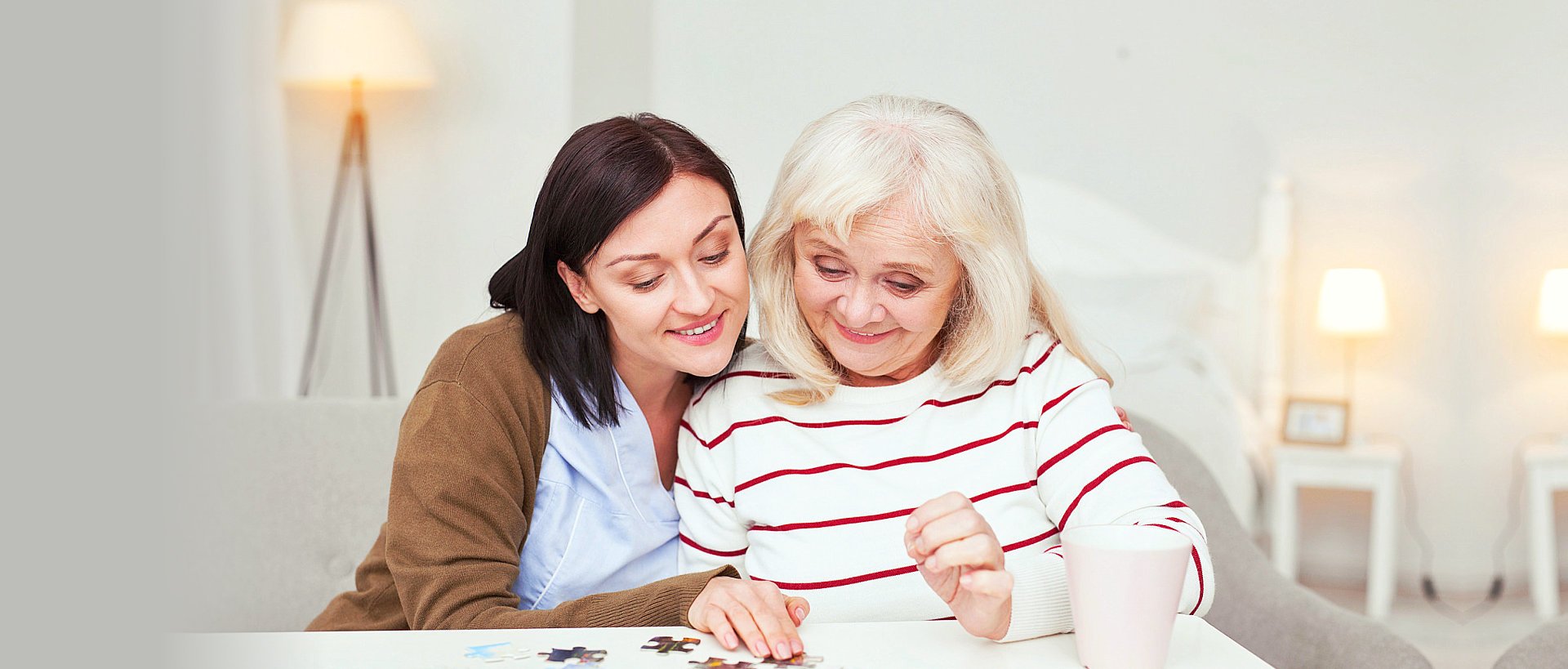 nurse and elderly woman playing jigsaw puzzle